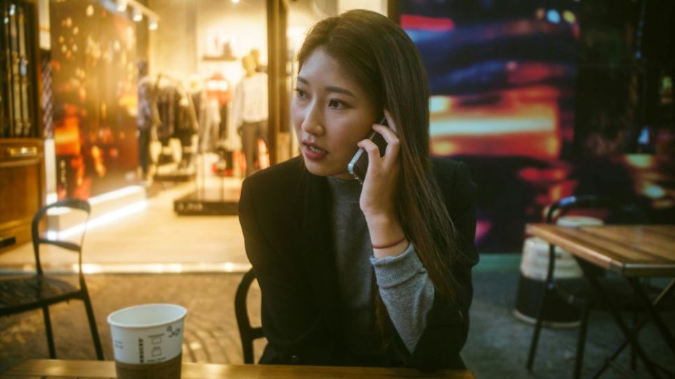 야외 카페에서 휴대폰으로 통화하는 여성