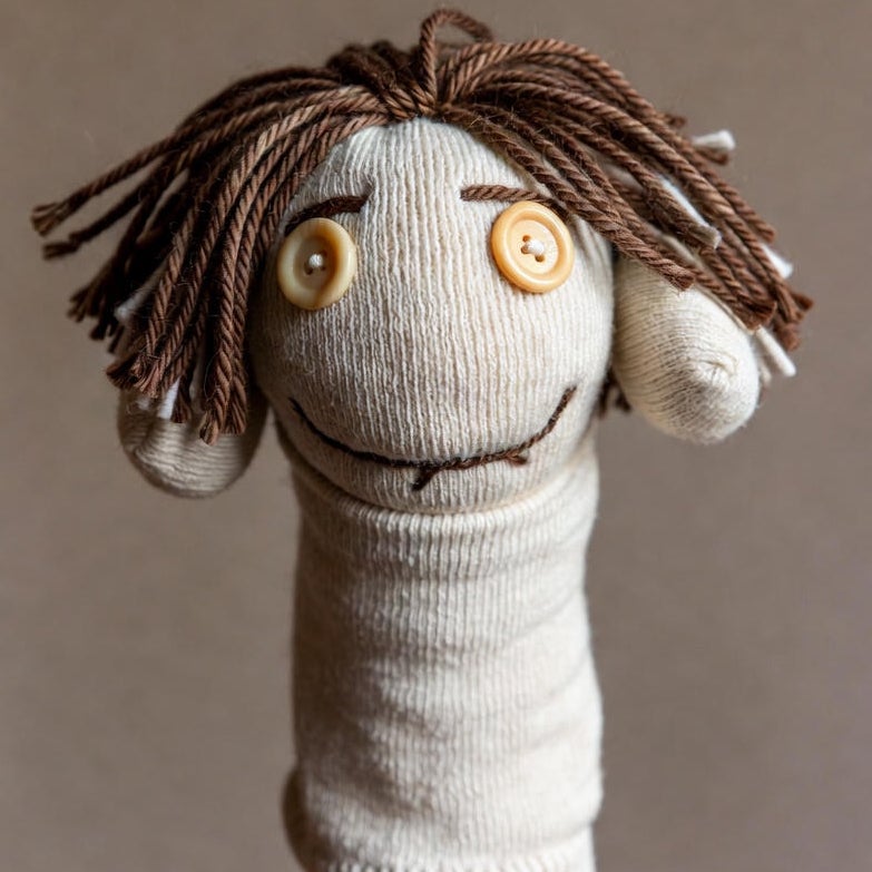 낡은 양말에 단추 눈과 실 머리카락을 달아 만든 손인형 — made out of an old sock의 예